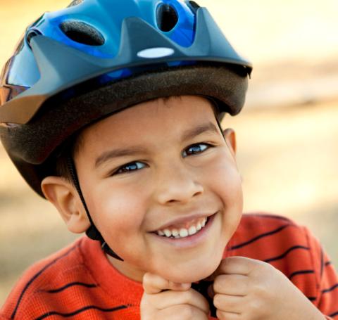 Smiling child wearing a blue bicycle helmet.
